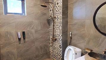 A bathroom with a shower, toilet, and a window.