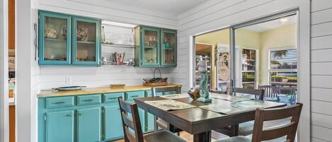 Une cuisine avec des meubles de couleur turquoise, une table à manger en bois et des chaises.