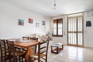Un comedor con una mesa y sillas de madera, un sofá y una ventana con persianas.