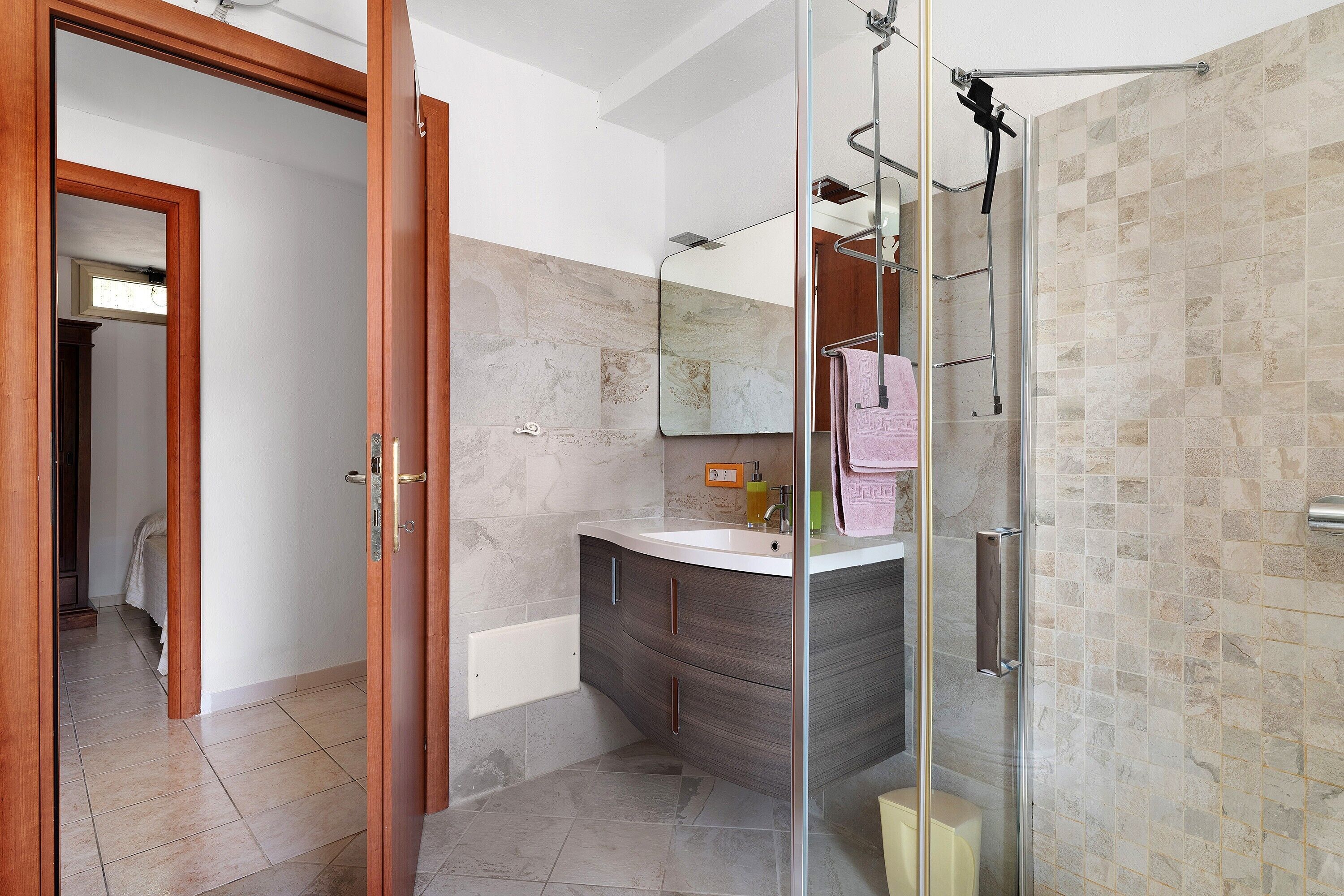 Une salle de bain avec une douche à parois de verre, un lavabo avec un miroir et un porte-serviettes.