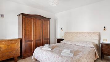Un dormitorio con cama, armario de madera, mesita de noche y lámpara de pared.