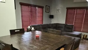 Et spiseområde med et træbord og stole, en sofa og et rødt stearinlys på bordet.