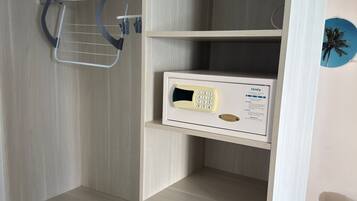 Quarto de hotel com minibar, pequena escrivaninha e telefone fixado na parede.