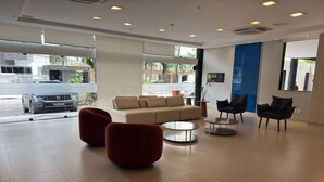 Eine moderne Lobby mit einer Couch, roten Sesseln und einem Couchtisch.