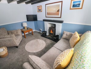 A living room with a fireplace, sofas, a television, and framed pictures on the wall. - Beacon House (Haverfordwest)