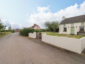 A quiet rural road with houses on either side, a gate, and a clear sky. - Beacon House (Haverfordwest)