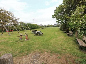 A grassy outdoor area with swings, picnic tables, and benches. - Beacon House (Haverfordwest)