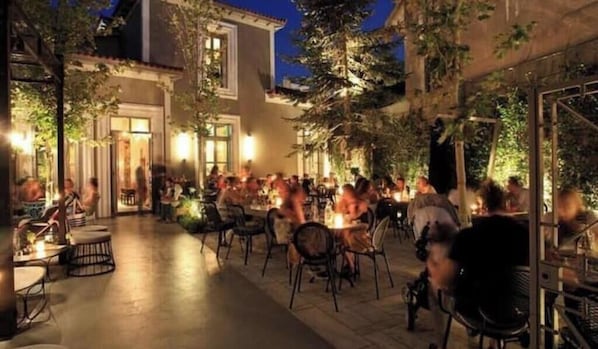 An outdoor dining area with tables and chairs, surrounded by buildings and trees. - ACROPOLIS VIEW -100% authentic Athens experience❤️ (Athina)