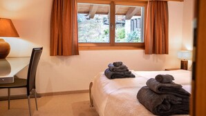 Une chambre d’hôtel avec un lit, une chaise, une table et une fenêtre avec des rideaux.