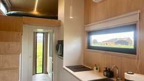 A modern kitchen with a large window, a built-in oven, and a sink. - Tiny House by Gad Bourgeois "La parenthèse nature" 8km from Pairi Daiza (Chièvres)