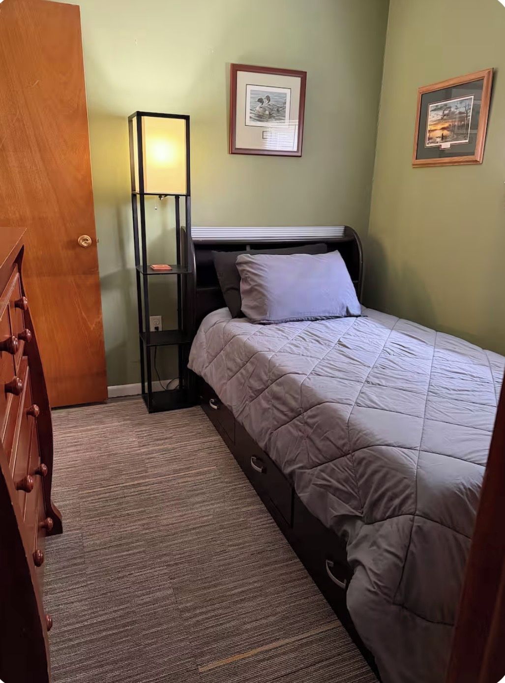 Una camera da letto con un letto, un comodino, una lampada e una cassettiera.