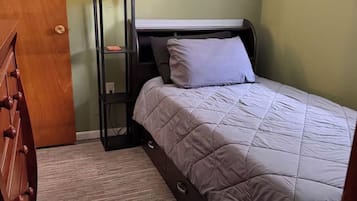 Una camera da letto con un letto, un comodino, una lampada e una cassettiera.