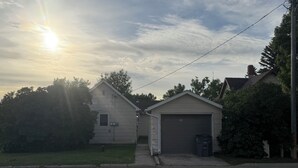A residential garage with a single door, a small attached shed, and a driveway leading to the house.