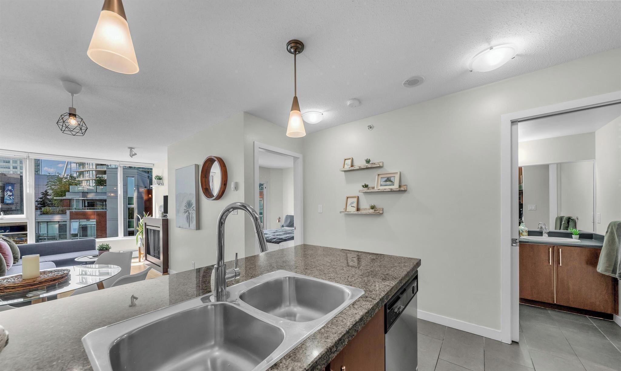 A modern kitchen with a double sink, granite countertop, and pendant lighting.