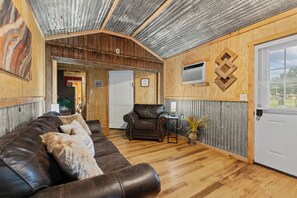Ein Wohnzimmer mit einer Ledersofa, einer Holztür und einem kleinen Tisch mit einer Pflanze.