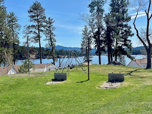 En ejendom ved søen med gyngestativ, træterrasse og udsigt over sø og bjerge.