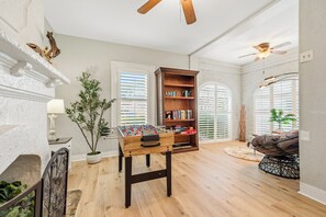 Ein Zimmer mit Fußballtisch, Bücherregal und Deckenventilator.