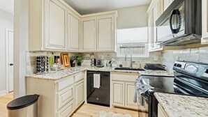 A kitchen with white cabinets, a black microwave, a dishwasher, and a stove. - Home near NRG - Sleep 8 - WolrdCup ready (Houston)