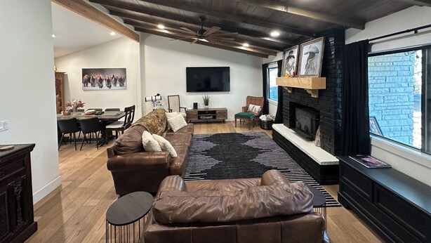 Een moderne woonkamer met een open haard, een grote televisie en een eethoek met een tafel en stoelen.