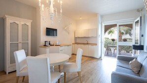 A modern kitchen with white cabinetry, a dining area with a round table and chairs, and a balcony with outdoor seating. - Apartment 'Don Onofrio - Domitilla' with Mountain View, Wi-Fi and Air Conditioning (Monopoli)