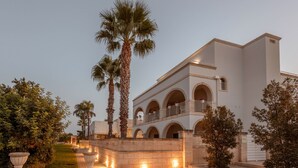 A multi-story building with arched balconies, a well-maintained lawn, and palm trees. - Apartment 'Don Onofrio - Domitilla' with Mountain View, Wi-Fi and Air Conditioning (Monopoli)