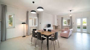 Un salon moderne avec un coin repas, un canapé rose et un téléviseur.
