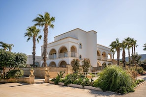 A building with multiple arches, palm trees, and a courtyard. - Apartment 'Don Onofrio - Ettore' with Mountain View, Wi-Fi and Air Conditioning (Monopoli)