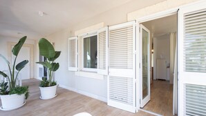 A room with a wooden floor, white walls, and a sliding glass door leading to a kitchen area. - Apartment 'Don Onofrio - Lavinia' with Mountain View, Wi-Fi and Air Conditioning (Monopoli)