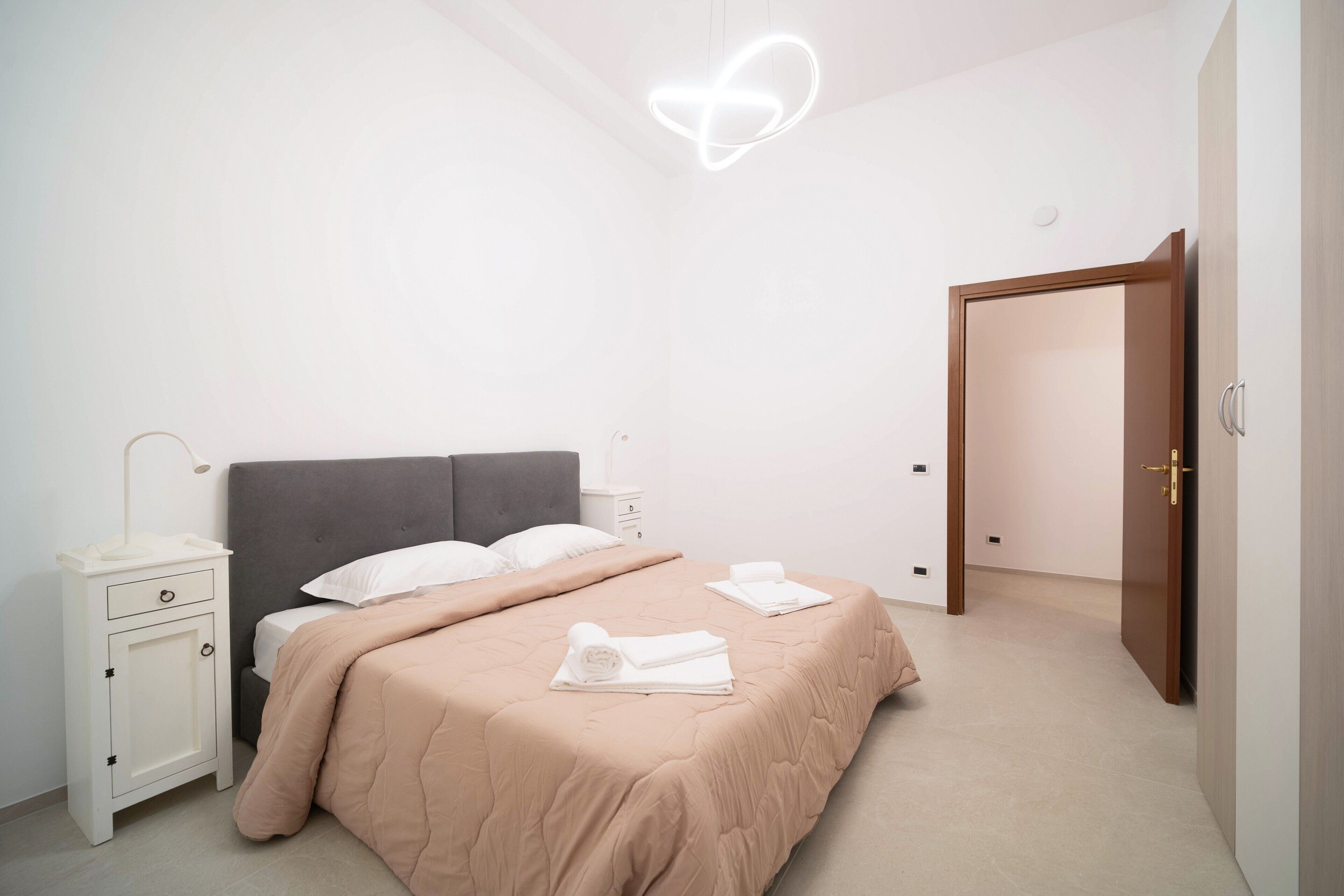 Quarto com cama, mesa de cabeceira e guarda-roupa.