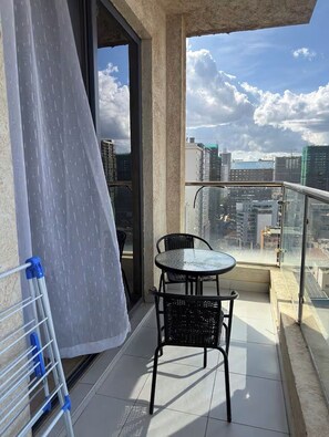 Un balcon avec une table et des chaises, une vue sur le paysage urbain et un étendoir.