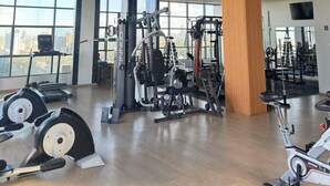 Un gimnasio con equipamiento de ejercicio, amplias ventanas y un diseño de techo de madera.