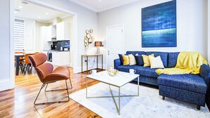 A modern living room with a blue sofa, a coffee table, and a brown chair. - Hybrid Resi Battersea (London)