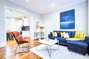 Ein modernes Wohnzimmer mit einem blauen Sofa, einem Couchtisch und einem braunen Sessel.