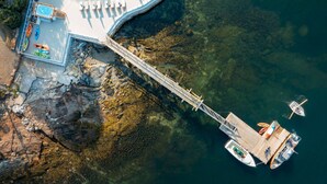 An aerial view of a resort with a swimming pool, lounge chairs, and a dock with boats. - Tanager Cottage | 3BR + 2 Porches + Fireplace (Boothbay Harbor)