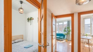 Een kamer met een bed, een deur die uitkomt op een balkon en een eethoek met een tafel en stoelen.