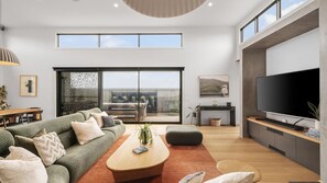 A modern living room with a sofa, coffee table, and TV. - Surfers Rest in Surf Beach (Surf Beach)