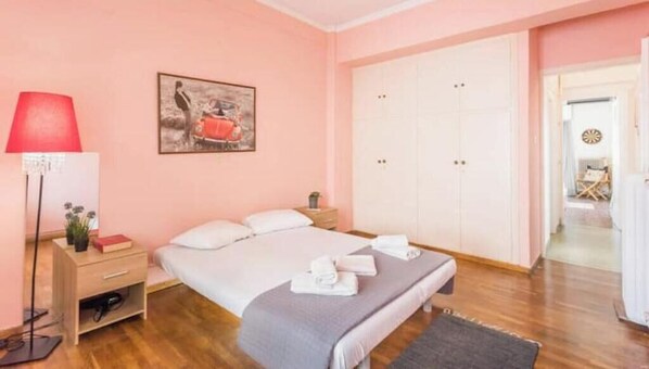 Een slaapkamer met een bed, nachtkastje, lamp en garderobe.