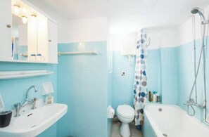 Een badkamer met een wastafel, toilet, bad en douche.