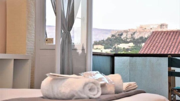 A hotel room with a view of a historic building, a bed with rolled towels, and a chair. - Acropolis View for Groups - 100% Athens experience (Athina)