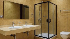 A modern bathroom with a glass shower enclosure, two sinks, a toilet, and a large mirror.
