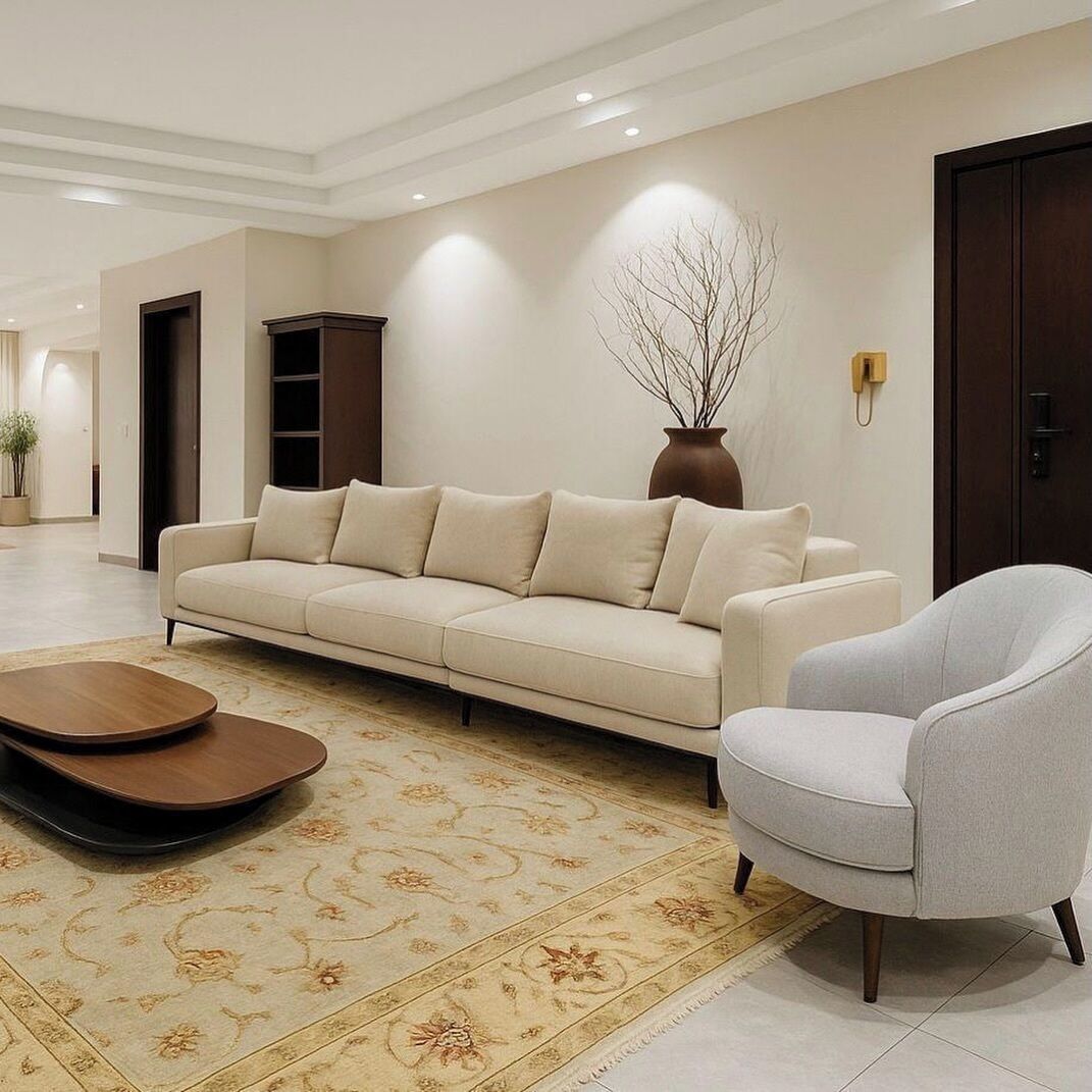 A modern living room with a sofa, armchair, and coffee table, a vase with branches, and a door.