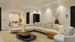 A modern living room with a sectional sofa, a small round coffee table, a grey armchair, and a decorative vase.