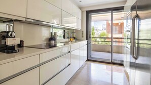 A modern kitchen with stainless steel appliances, a coffee machine, and a sliding glass door leading to a balcony. - Modern Appartement a/c 2br/4p - Cannes (Cannes)