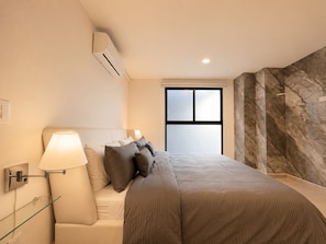 Ein Schlafzimmer mit Bett, Nachttischlampen, einem Fenster und einer Marmorwand.