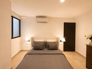 Ein Schlafzimmer mit Bett, Nachttischlampen, einer Klimaanlage und einer Tür.