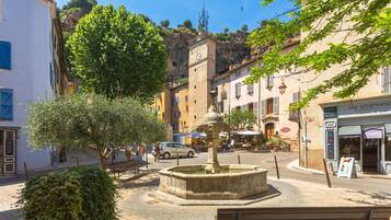 Una plaza de pueblo con una fuente, bancos y edificios con tiendas.