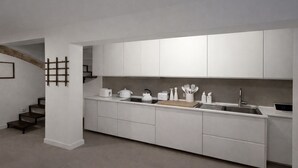 Una cocina moderna con armarios blancos, estufa integrada y pileta de acero inoxidable.