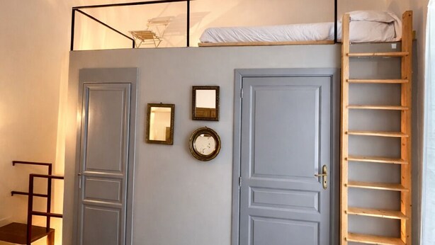Un dormitorio con literas, una escalera, una puerta y un estante.