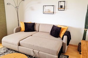 Un canapé modulable recouvert d’un tissu clair, agrémenté de deux coussins noirs et de deux coussins jaunes.