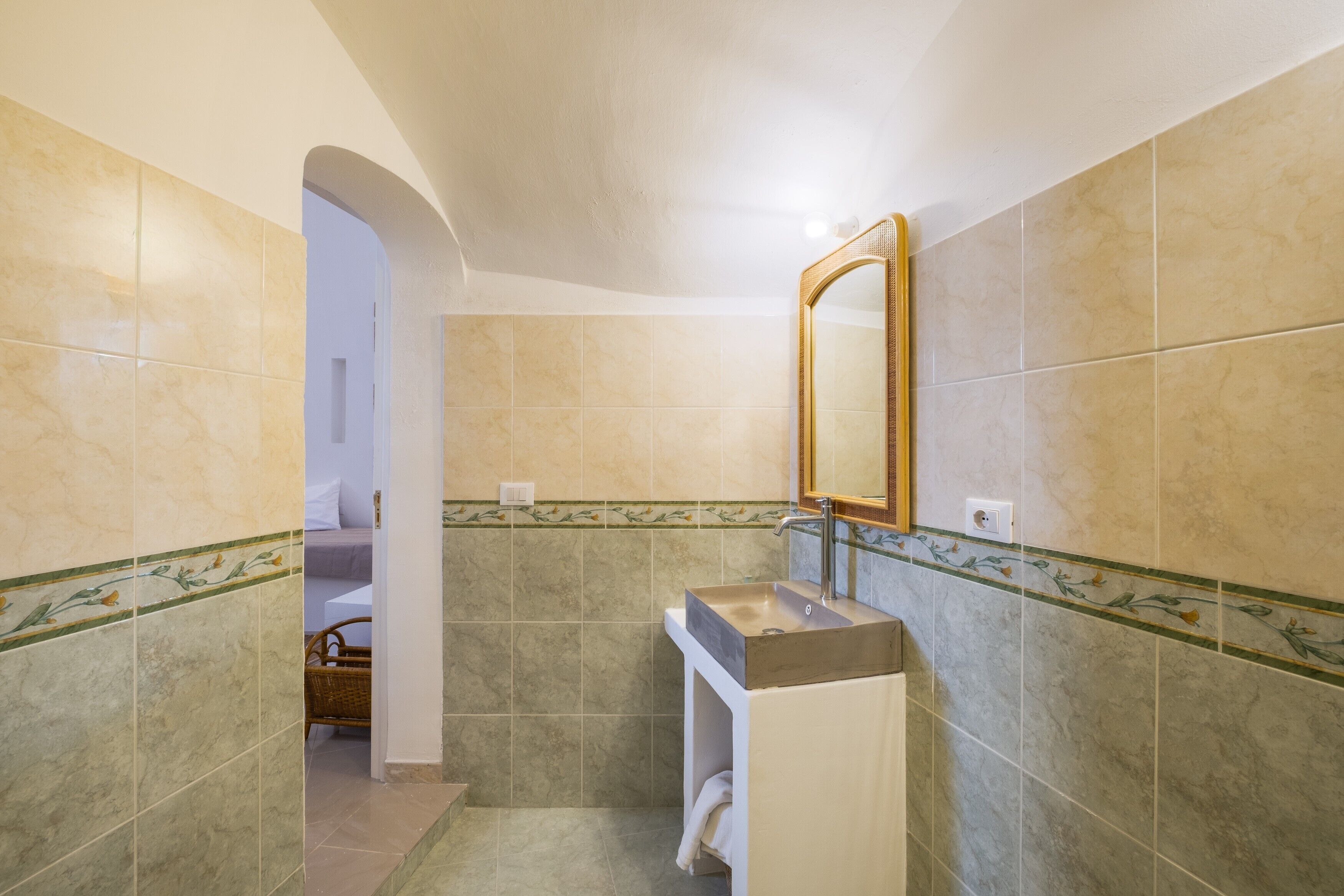 Ein Badezimmer mit Waschbecken, Spiegel und gefliesten Wänden.
